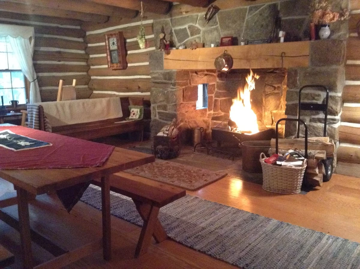 A fire burning in the large stone fireplace inside the log home.